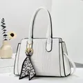 Detail of white crocodile-embossed handbag with leopard silk scarf and gold hardware accents - Off White