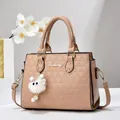 Fashion apricot crossbody bag with triangular embossed texture and plush charm accessory - Khaki