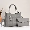 Detail of grey pebbled faux leather tote with diamond stitching and leaf charm - Gray