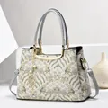 Close-up of jacquard embroidery fabric and gold leaf pendant on a Chinese style handbag - Beige