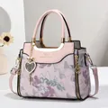 Pink structured handbag with floral embroidery and gold accents shown with accessories - Pink