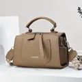 Detail of khaki leather Boston bag with litchi texture and woven shoulder strap - Khaki