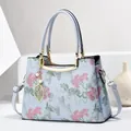 Light blue embroidered tote bag with pink floral patterns and golden metal handles - Blue