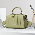 Detail view of green pebble leather Boston bag with stylish geometric woven strap - Green