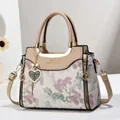 Detail of floral embroidery on beige handbag with gold hardware and heart charm - Apricot