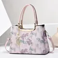 Elegant pink handbag with floral embroidery and gold leaf pendant in a minimalist setting - Pink