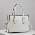 Witte Saffiano leren handtas met gouden hardware en verstelbare riem op marmeren voet - Wit