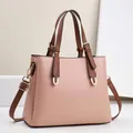Elegant pink lychee leather handbag with brown handles and adjustable crossbody strap - 28cm x 11cm x 22cm / Pink
