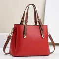Detailed close-up of red lychee pattern leather handbag with brown handles and gold hardware - 28cm x 11cm x 22cm / Red