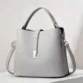 Detail of grey bucket bag showing litchi grain leather texture and silver buckle - Length 23 Width 12 Height 21 / Gray