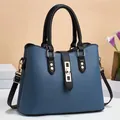 Blue lychee grain leather handbag with black handles and gold hardware on a desk - Blue