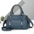 Detailed macro view of litchi textured leather handbag featuring decorative metal zippers - Blue