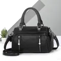 Detail of black litchi grain texture and engraved silver hardware on a leather tote bag - Black