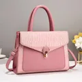 Detail view of pink crocodile-embossed leather texture and gold twist lock closure - Pink