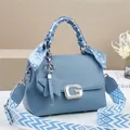 Detail of light blue crossbody bag featuring a silk scarf handle and wide woven strap - Blue