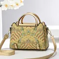 Detail of golden brocade handbag with traditional Chinese patterns and metal handle - Gold