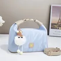 Detail of light blue textured handbag with plush charm and elegant gold metal lock - Blue