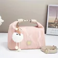 Close-up of pink pleated glossy handbag featuring plush charm and metallic logo detail - Pink