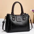Close-up of contrast stitching and lychee grain texture on dark leather shoulder bag - Black