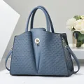 Fog blue leather handbag with woven texture panels and round metal lock closure - Blue
