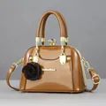 Brown shell-shaped patent leather handbag with floral charm and gold metal frame - Shiny Brown