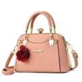 Rosa Muscheltasche aus Kunstleder mit Tragegriffen, Goldbeschlägen und rotem Rosenanhänger - Hellrosa