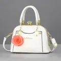 Elegant white shell bag in glossy patent leather with gold clasp and floral charm - Glossy White