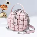 Detail of round quilted shoulder bag in light pink with metal clover pendant and zipper - Pink