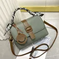 Détail d'un sac à main vert sauge, texture litchi et poignée décorée d'un foulard en soie - Vert