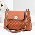 Close-up of brown quilted shoulder bag with gold diamond-encrusted twist lock detail - Yellow