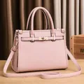 Pink lychee texture Kelly bag with golden twist lock on wooden desk background - Pink