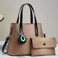 Detalle de textura de cocodrilo y colgante de perlas en el bolso de mano marrón - Caqui