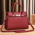 Detail of burgundy pebbled leather handbag with golden lock and adjustable strap - Burgundy