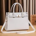 Close-up of white lychee pattern leather and gold twist lock on the crossbody bag - White