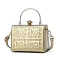 Close-up of golden hard shell evening bag with KOKO rivet lettering and jewel clasp - One Size / Gold