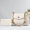 Detail view of cream quilted shoulder bag with gold heart lock and matching long wallet - White