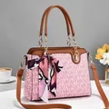 Detailaufnahme der rosa Monogramm-Handtasche mit Seidenschal und Goldketten-Akzenten - Rosa