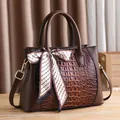 Classic brown crocodile embossed handbag with silk scarf on dark wooden handle - Coffee