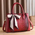 Detail of burgundy crocodile embossed handbag with silky scarf and gold hardware - Burgundy