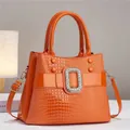 Vibrant orange patent leather handbag with lizard pattern and crystal buckle detail - Orange