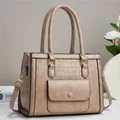 Detail of light brown tote bag featuring crocodile pattern texture and golden hardware - Apricot