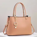 Close-up of litchi pattern leather tote bag with gold smiley face pendant and strap - Pink
