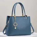 Classic navy blue leather tote bag with gold hardware and stylish charm detail - Blue