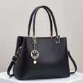 Close-up of black pebble leather tote with gold hardware and smiley face charm detail - Black