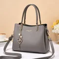 Detail of grey leather handbag with golden lettering, pearl charm and metal hardware - Gray