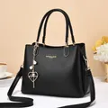 Bolso minimalista de cuero negro con detalles dorados y colgante de corazón de perla - Negro