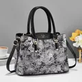 Women's floral print handbag with black handles and gold hardware in a lifestyle setting - Black