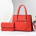 Close-up of red leather tote bag and matching envelope wallet with gold metal hardware - Red