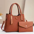 Detailed view of brick red embossed tote bag with matching envelope clutch and gold hardware - Earthy Yellow