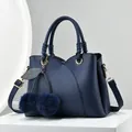 Navy blue lychee pattern leather handbag with cherry pom-pom charm and adjustable strap - Blue